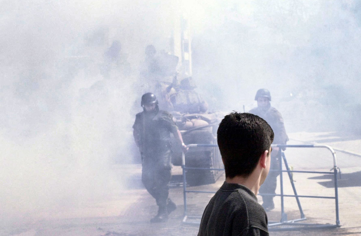 Macedonian police officers close down a road after Macedonian tanks returned from the hills around Tetovo.