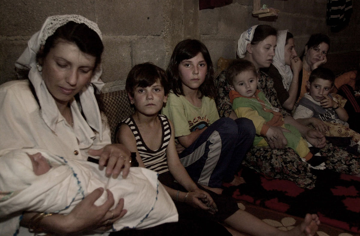 Women and children hurdle together in a makeshift bomb shelter  in the village of Otlja.